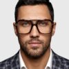 A man in a suit and glasses stands confidently, showcasing a professional appearance.