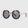 Round black plastic sunglasses with gold details, showcasing a stylish and modern design.