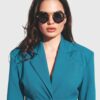 A woman in a blue suit and sunglasses stands confidently, exuding professionalism and style.