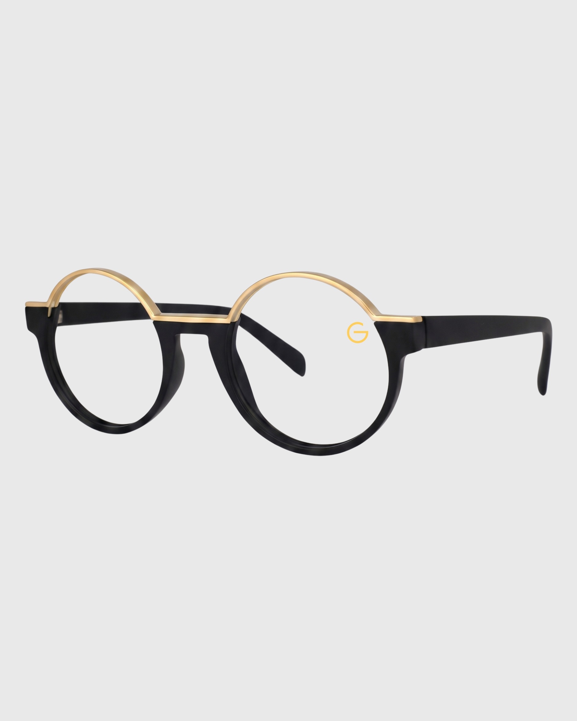 A pair of eyeglasses featuring gold rims and black frames, resting on a flat surface.