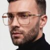 A man with glasses and a beard wearing a black turtleneck, looking thoughtfully to the side.