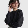 A woman with glasses wearing a black sweatshirt, looking directly at the camera with a neutral expression.