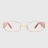 A pair of glasses featuring gold frames with a vibrant pink and red design on the arms.