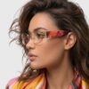 A woman with glasses featuring vibrant, colorful patterns, smiling and looking directly at the camera.
