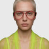 A model showcases bright red glasses paired with a vibrant yellow shirt, highlighting a bold fashion statement.