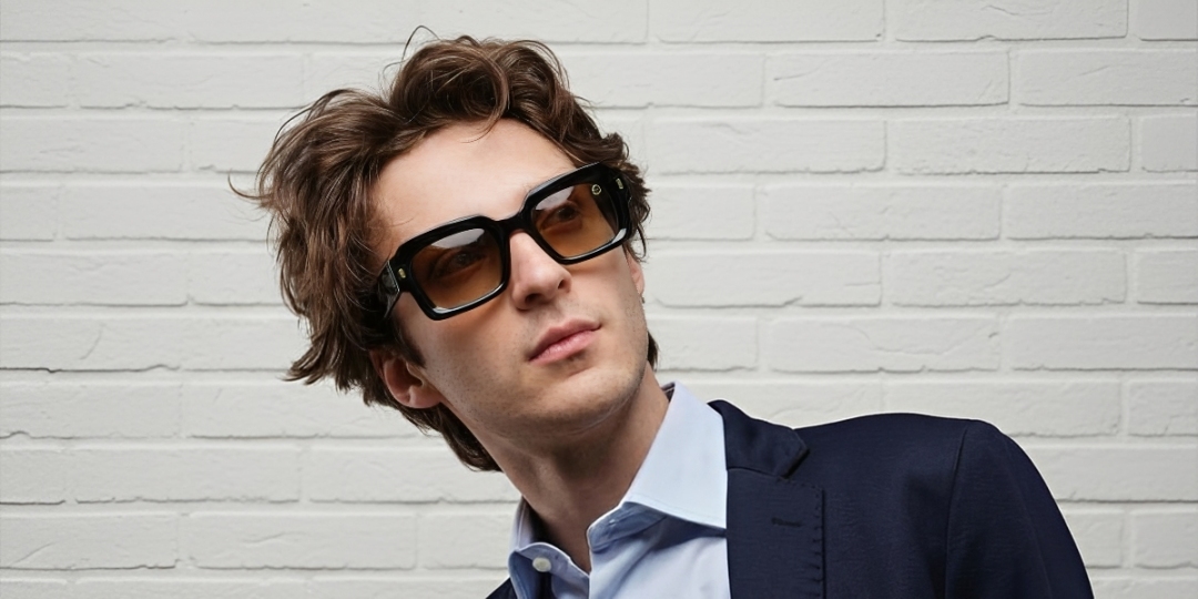 A man in a suit and sunglasses stands confidently, exuding a professional and stylish demeanor.