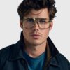 A man wearing glasses and a jacket, standing confidently with a neutral expression.