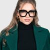 A model showcases a stylish green coat paired with fashionable glasses, highlighting contemporary fashion trends.