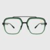 A pair of black-framed glasses featuring green lenses, resting on a flat surface.