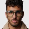 A man with glasses featuring green frames, looking directly at the camera with a neutral expression.