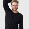 A man wearing glasses and a black sweater, looking directly at the camera with a neutral expression.
