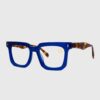 A pair of eyeglasses featuring blue frames and tortoise shell accents, displayed against a neutral background.
