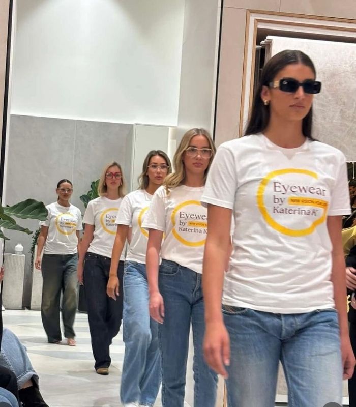 A group of women in white shirts and sunglasses, smiling together outdoors, showcasing a sense of camaraderie and style.