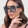 A model wearing black sunglasses with a stylish silver frame, showcasing a chic and modern look.