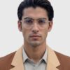 A man in a tan suit and glasses stands confidently, showcasing a professional appearance.