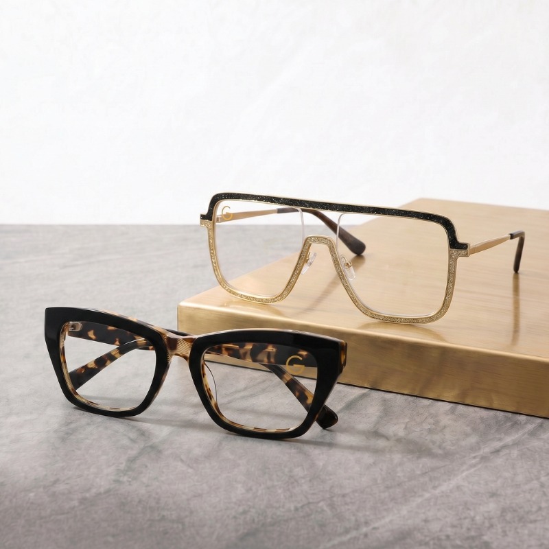Two pairs of glasses resting on a wooden table, showcasing different styles and colors.